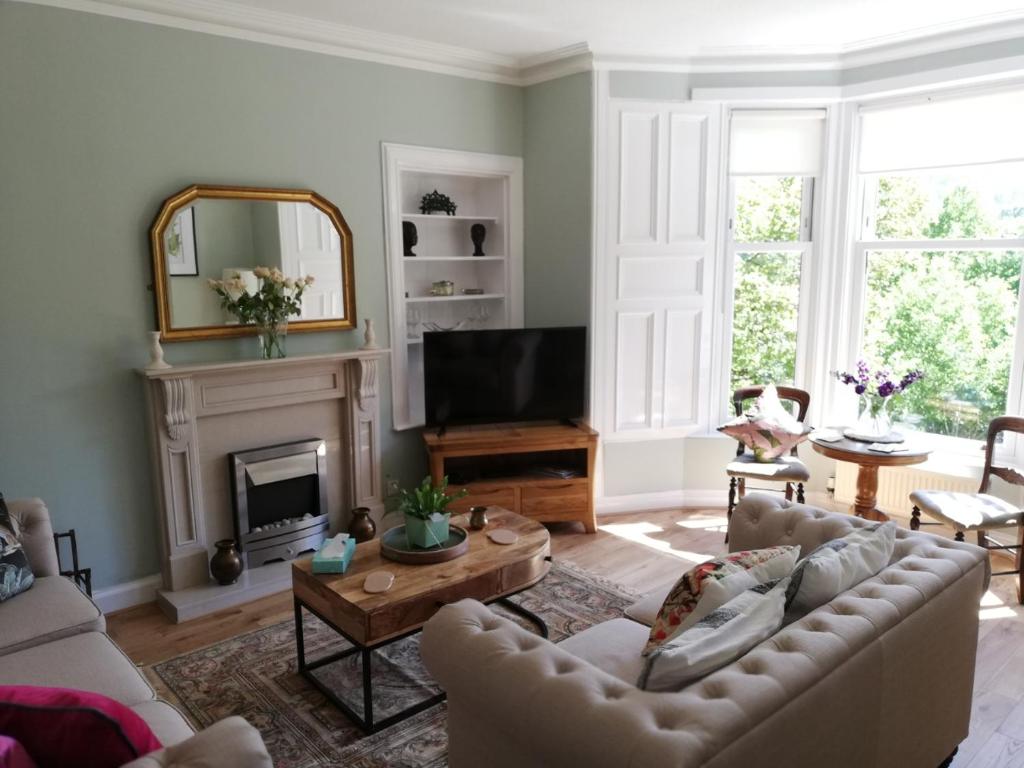 a living room with a couch and a fireplace at Woodburn ground-floor apartment in quiet setting in Pitlochry in Pitlochry