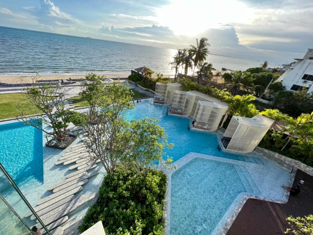 una imagen de una piscina con sillas y el océano en Veranda Residences Pattaya By Phung en Jomtien Beach