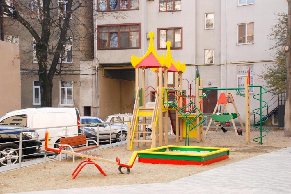 a playground in front of a building with cars at Комфортні апартаменти 82 in Ivano-Frankivsʼk