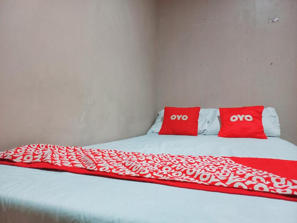 ein Bett mit zwei roten Kissen darüber in der Unterkunft SPOT ON 91336 Guesthouse Tarumanegara in Karawang