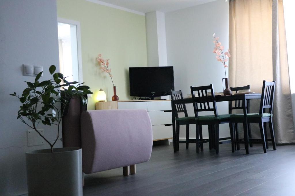 ein Wohnzimmer mit einem Tisch und Stühlen sowie einem TV in der Unterkunft Bran's Apartment in Cluj-Napoca