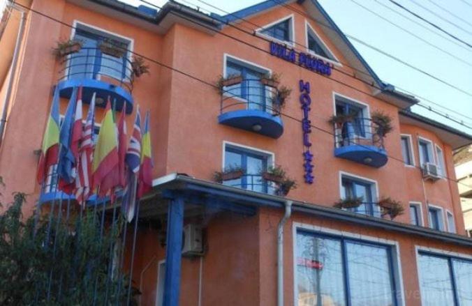 un bâtiment orange avec des fenêtres et des drapeaux. dans l'établissement Vila Flora, à Mediaş