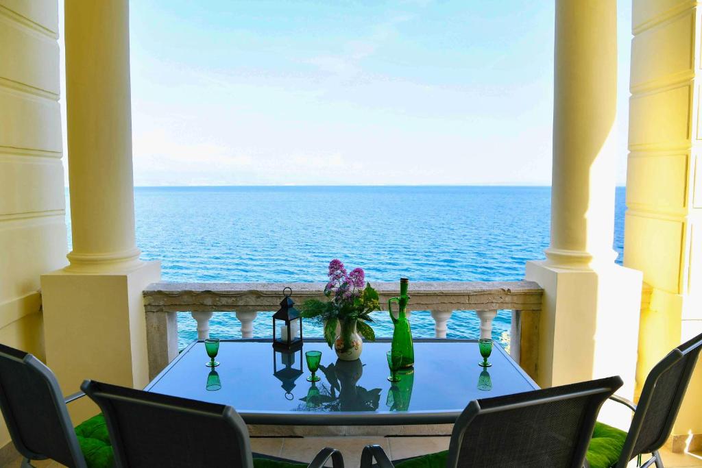 a table on a balcony with a view of the ocean at Apartment Carissima-Direct on sea, Lovran-Opatija in Lovran