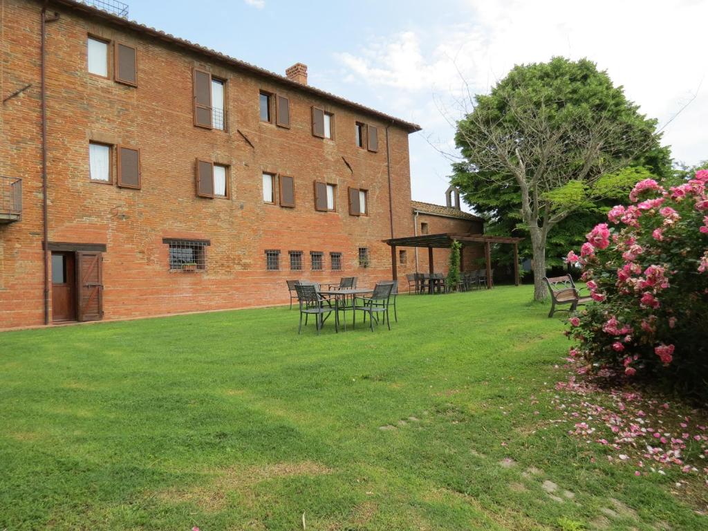 a brick building with tables and chairs in a yard at Agriturismo Borgo Del Papa in Badia