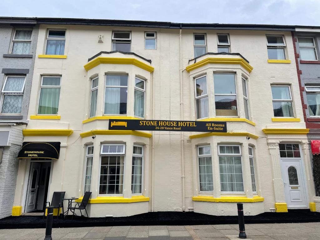 a white building with yellow trim on a street at The Stone House Hotel in Blackpool