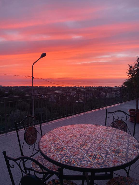 a table and chairs on a patio with a sunset at Casa Vacanza Elena in Capo dʼOrlando