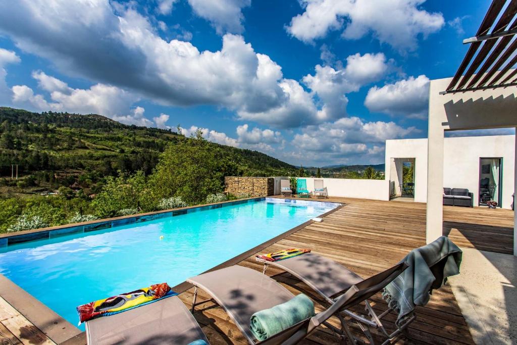 a swimming pool with two chairs and a mountain at Villa Blanche, Contemporary, Cathars, Couiza, Carcassonne in Couiza