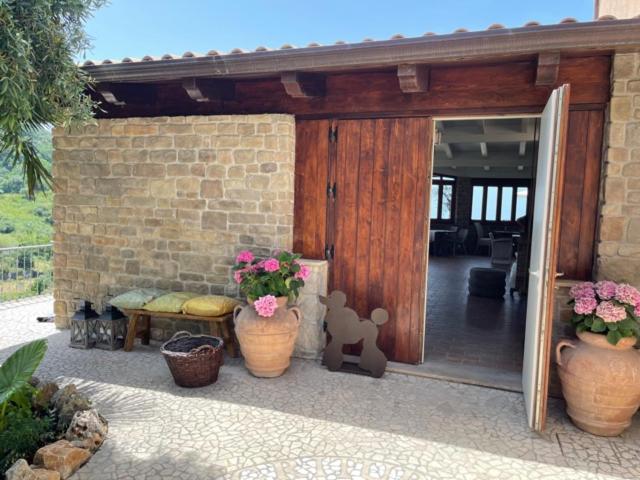 una puerta abierta a una casa con macetas de flores en La Pastorella en Maierà