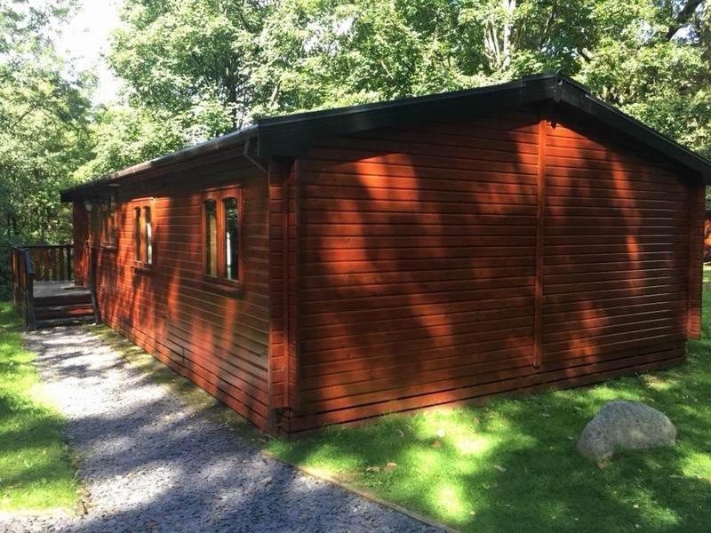a wooden cabin sitting on the grass in a yard at L09 - The Snowdon Spa with Hot Tub in Bethesda