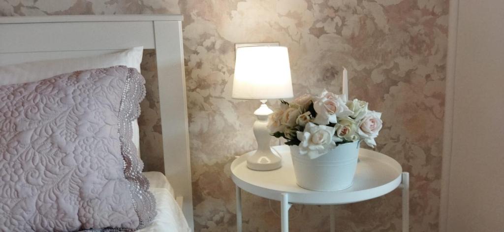 a bedroom with a bed and a table with a lamp and flowers at Apulum Apartment in Alba Iulia
