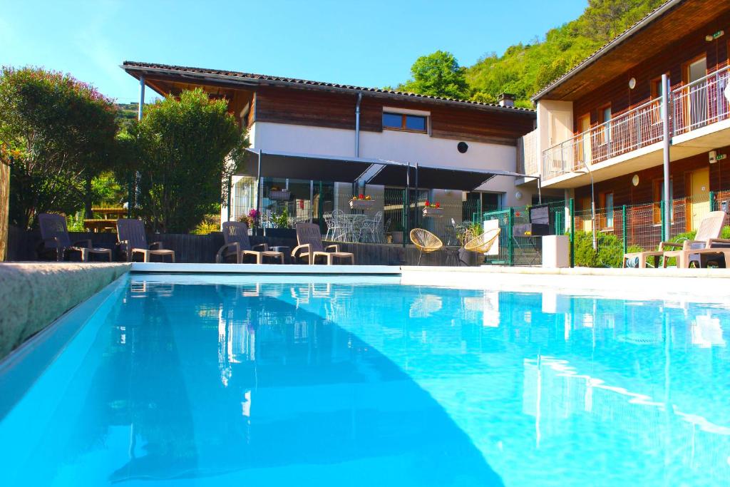 a swimming pool with blue water in front of a building at Hotel Le Vanséen in Les Vans