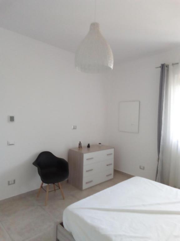 a bedroom with a black chair and a dresser at Villa Anna Maria in Polignano a Mare