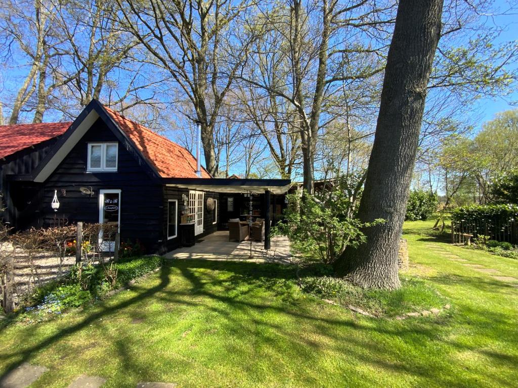 una casa negra con un árbol en el patio en B&B de Tuinfluiter, en Nieuwleusen