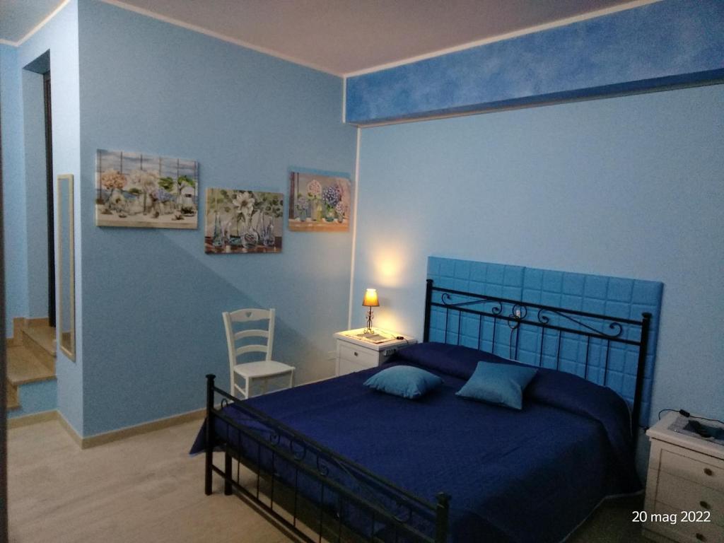 Un dormitorio azul con una cama y una silla. en ALLOGGIO BLU nel CUORE DI SORIANO, en Soriano nel Cimino