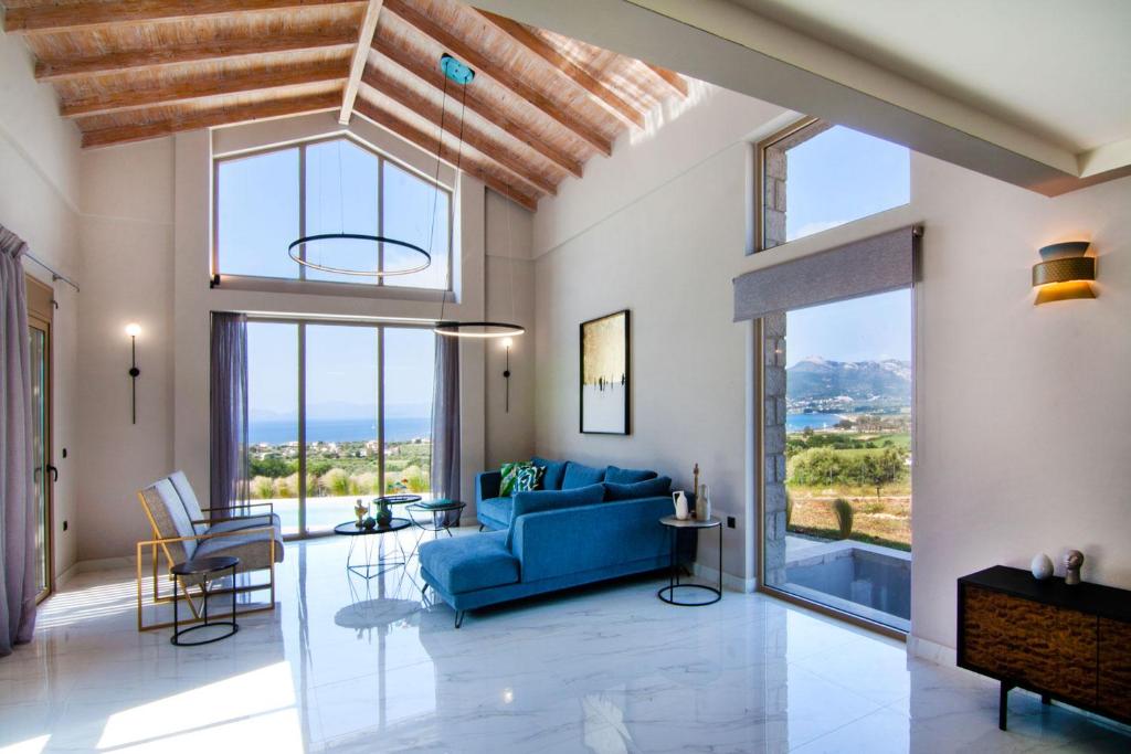 a living room with a blue couch and large windows at Villas Mandalos in Paleros