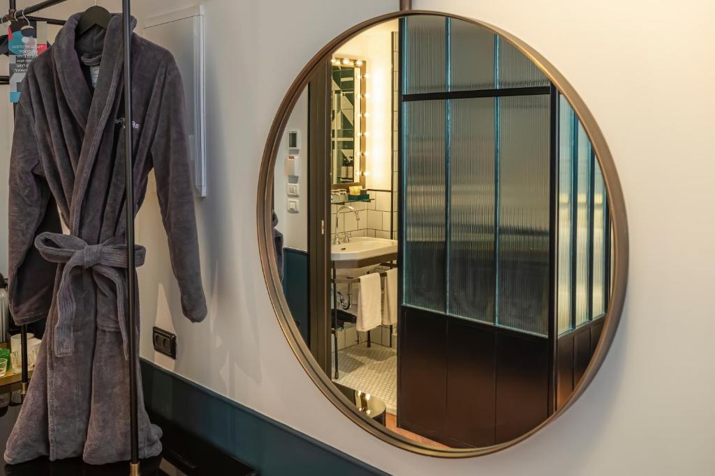 a mirror on a wall in a bathroom with a robe at Backstage Hotel - an Atlas Boutique Hotel in Tel Aviv