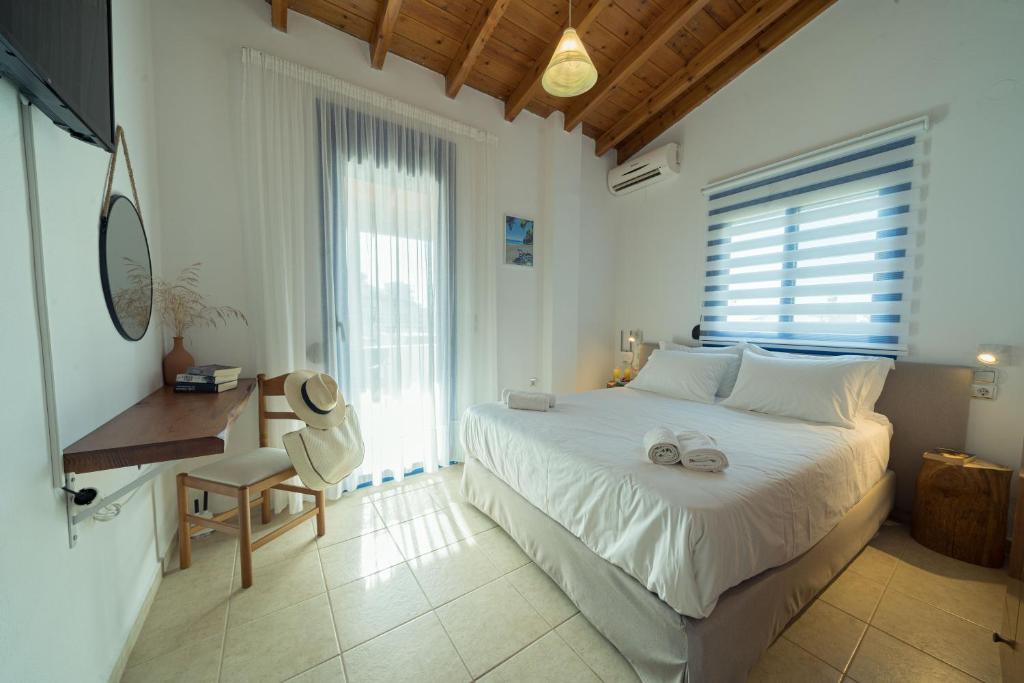 a bedroom with a white bed and a desk and window at Sunset Home Crete in Paránimfoi