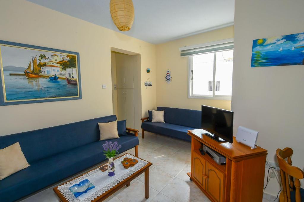 een woonkamer met een blauwe bank en een tv bij The Blue Mile in Paralimni
