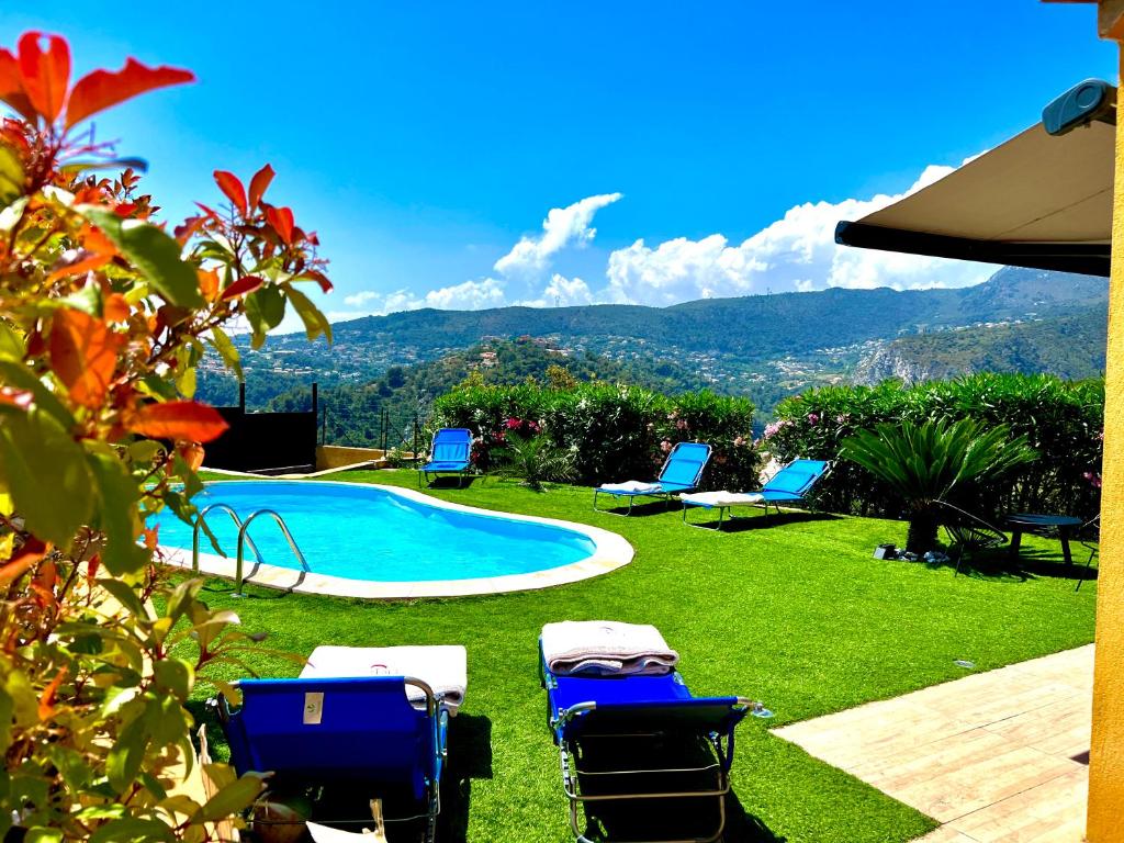 a yard with chairs and a swimming pool and mountains at Villa Les Anges in Saint-Andre-de-la-Roche