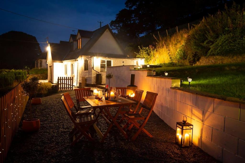 - une table et des chaises dans l'arrière-cour la nuit dans l'établissement Hillside Cottage, countryside views near Llangollen, à Corwen