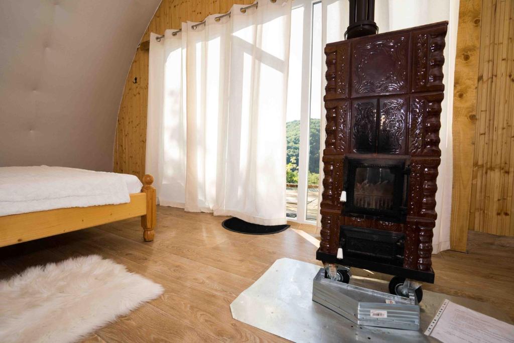 a room with a fireplace and a bed and a window at Sunrise Glamping Retreat in Galeşu