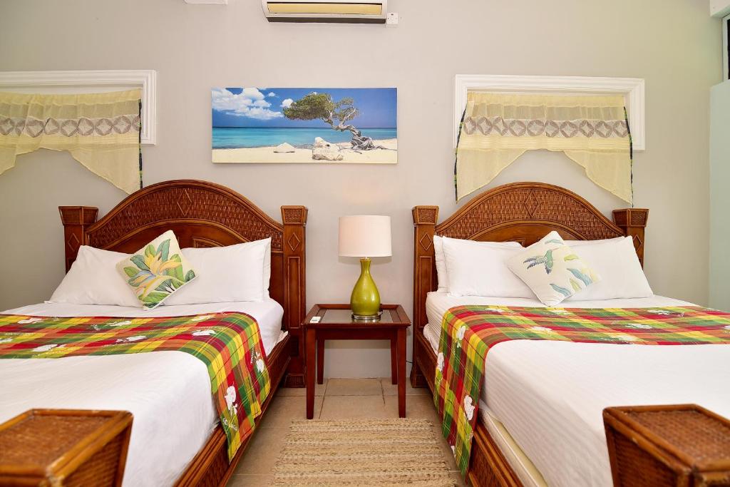 a bedroom with two beds and a table with a lamp at BeachFront Villa in Gros Islet