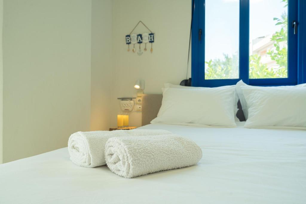a bedroom with a white bed with blue windows at Sunset Home Crete in Paránimfoi
