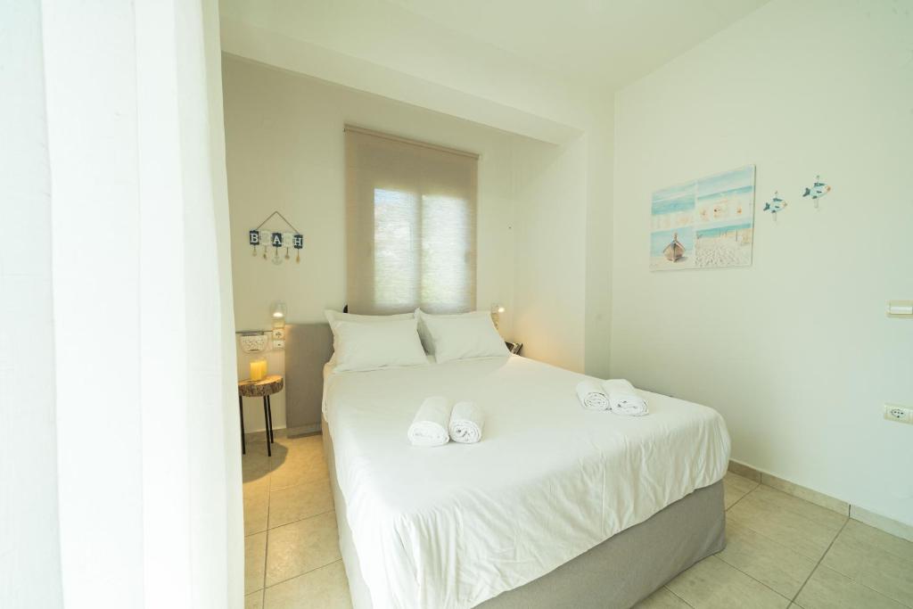 a bedroom with a white bed with white sheets at Sunset Home Crete in Paránimfoi