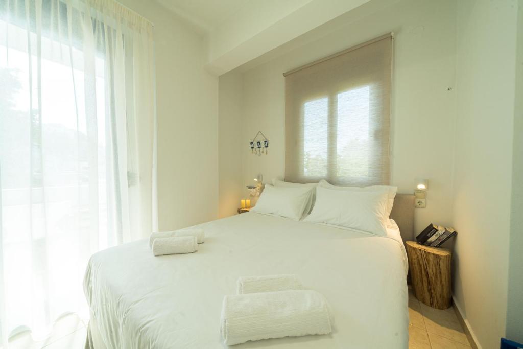 a white bedroom with a large white bed with white pillows at Sunset Home Crete in Paránimfoi