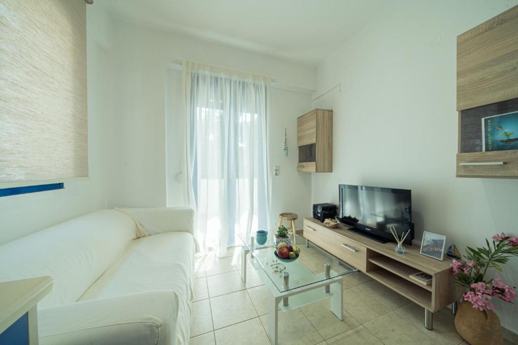 a living room with a white couch and a television at Sunset Home Crete in Paránimfoi