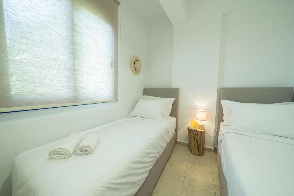 two twin beds in a room with a window at Sunset Home Crete in Paránimfoi