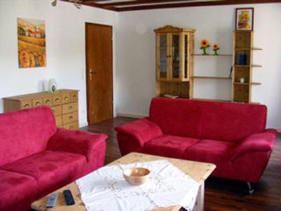 ein Wohnzimmer mit zwei roten Sofas und einem Tisch in der Unterkunft Ferienhäusle Sonnenblume Titisee in Titisee-Neustadt