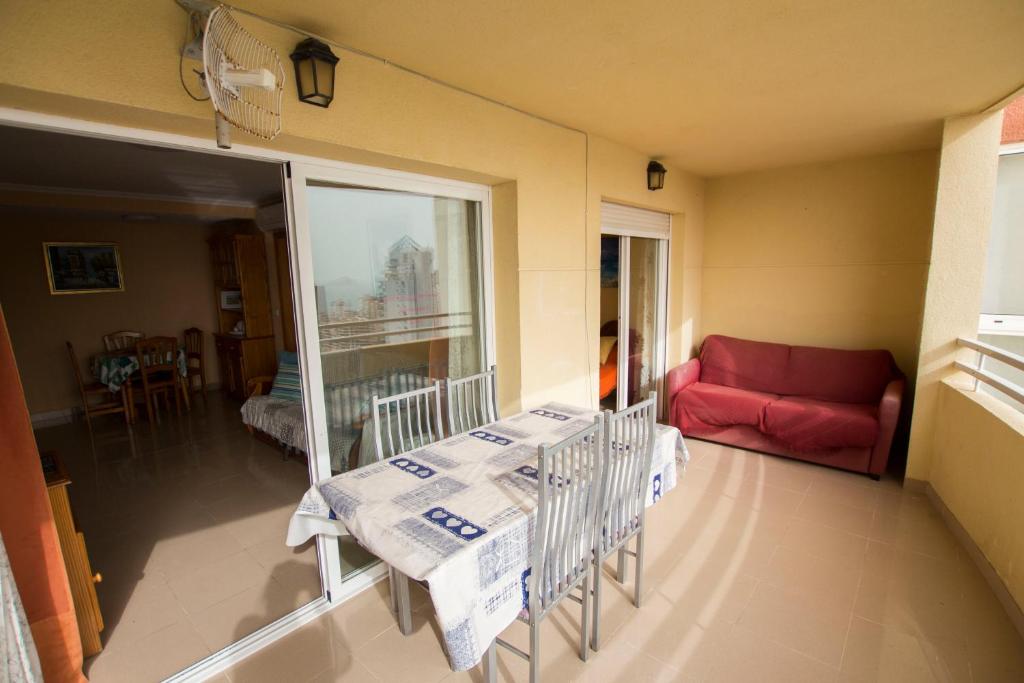 een woonkamer met een tafel en een rode bank bij Bonito apartamento cerca de la playa, planta alta. in Cala de Finestrat