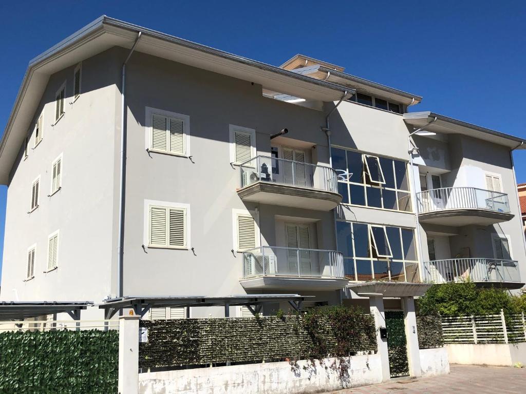 a white apartment building with balconies and a fence at Terrazze Marinella - Appartamenti - Case vacanze in Pizzo
