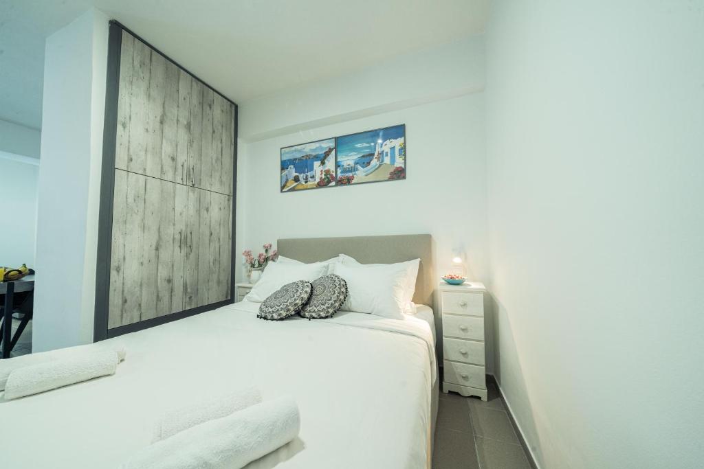 a white bedroom with a white bed and a desk at Sunset Home Crete in Paránimfoi