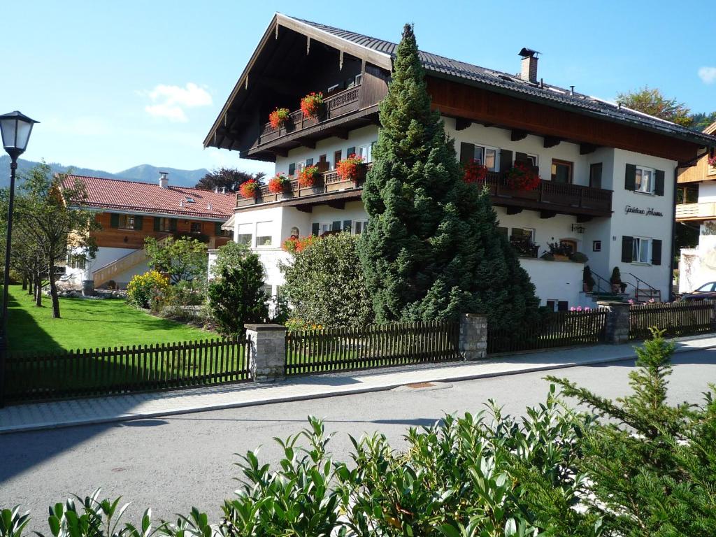 un gran edificio blanco con una valla y un árbol en Gästehaus Johanna, en Bad Wiessee