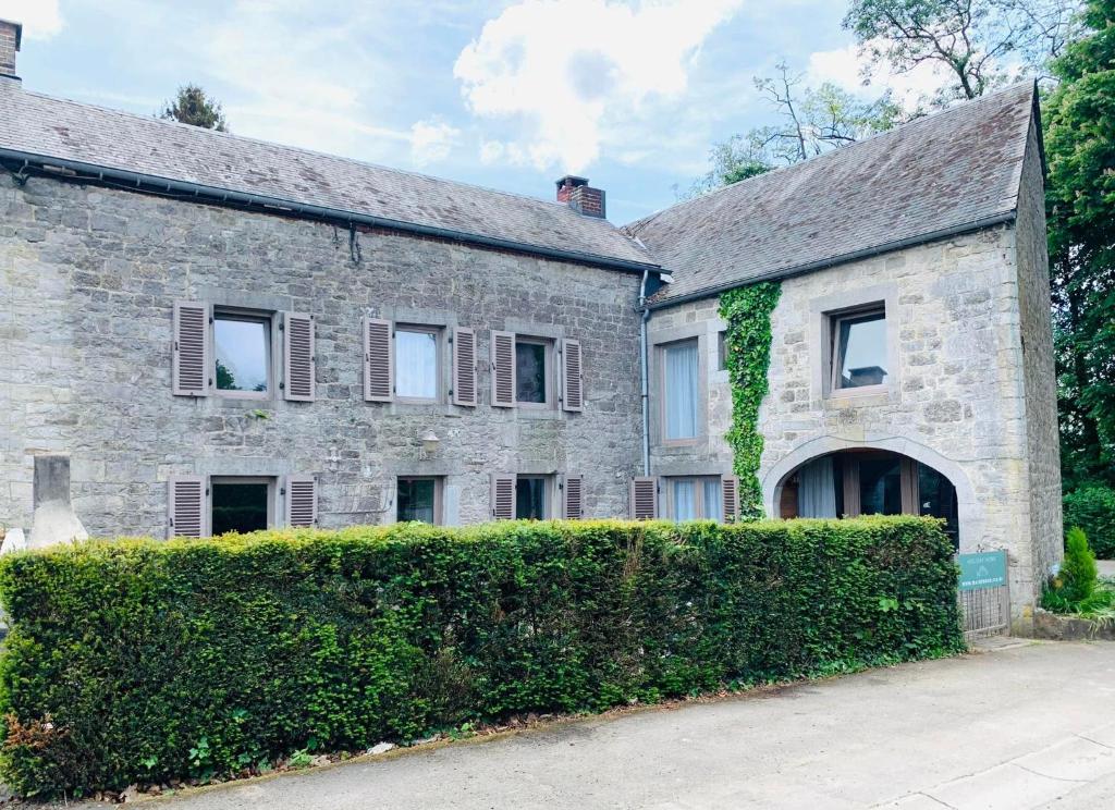 an old stone house with a hedge in front of it at Charming holiday house near Durbuy in Durbuy