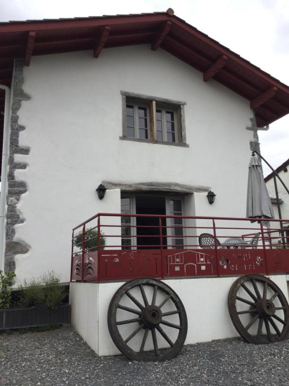 a white house with a red and white cart in front of it at Larrondoa maison in Saint-Esteben