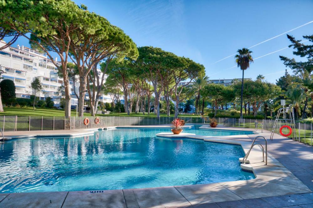 una piscina en un parque con árboles en PLAYAS DEL DUQUE, PUERTO BANUS, GOLF .PLAYA Y COMPRAS, en Marbella