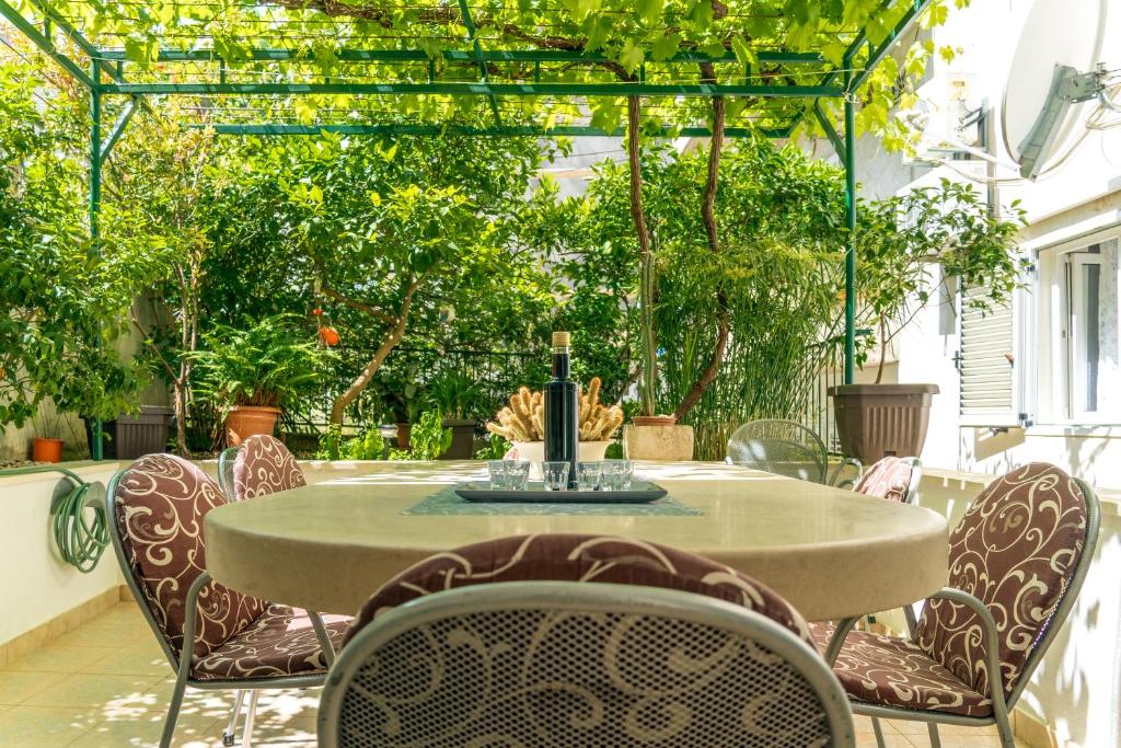 a table and chairs on a patio with trees at Comfort Apartment Dorin in Makarska