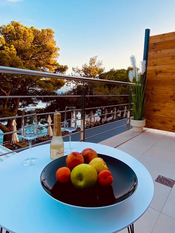 a bowl of fruit on a table with a bottle of wine at Zlatni Rat Beach Resort in Bol