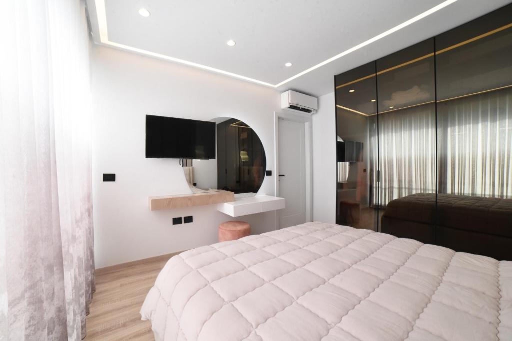 a bedroom with a large white bed and a television at San Pietro villa in Durrës