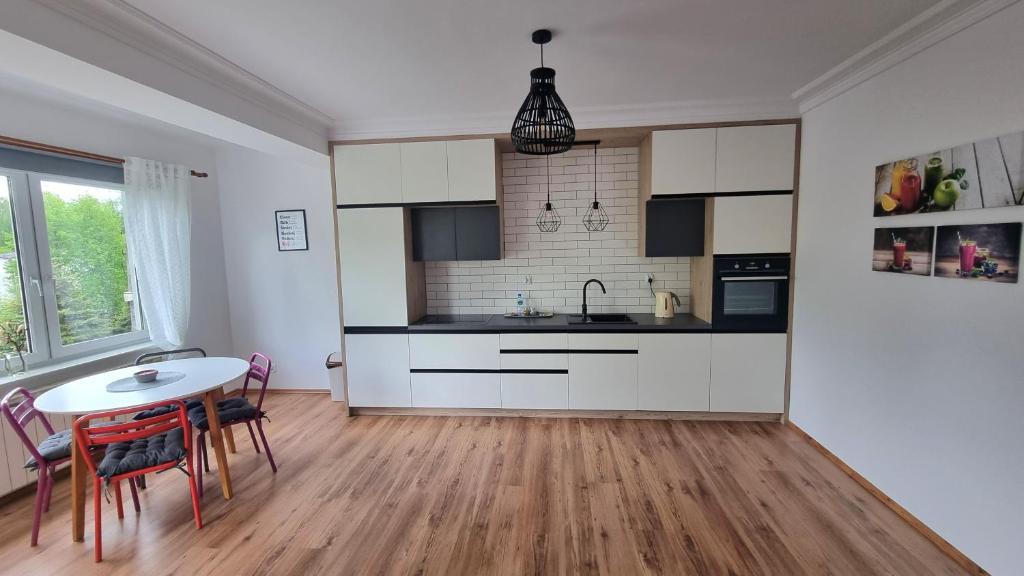 a kitchen with white cabinets and a table and chairs at Dwupokojowy Apartament z widokiem na kanał Augustowski in Augustów