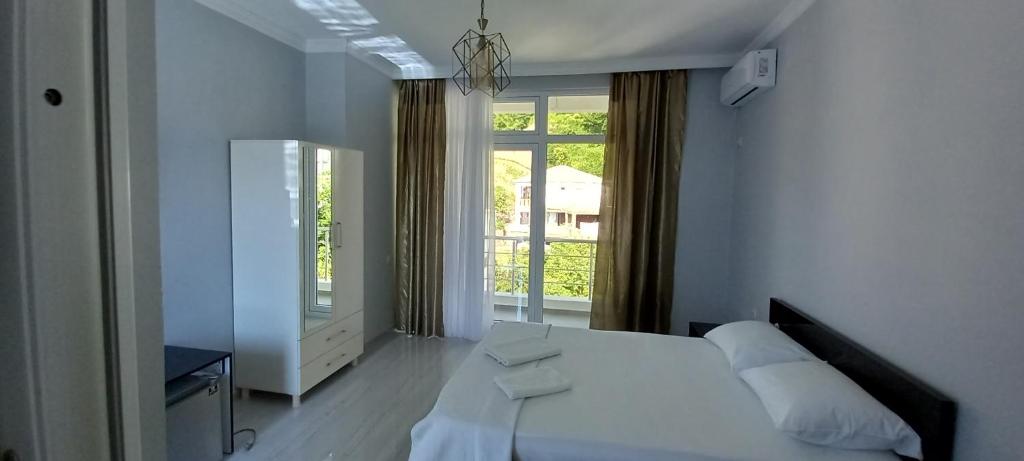 a white bedroom with a bed and a window at Guest House Marineza in Gonio