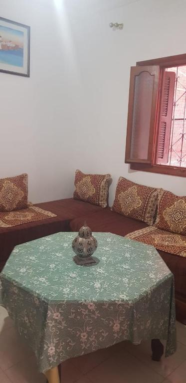 ein Wohnzimmer mit Tisch und Couch in der Unterkunft Appartement 2 éme étage dans la médina kédima in Asilah