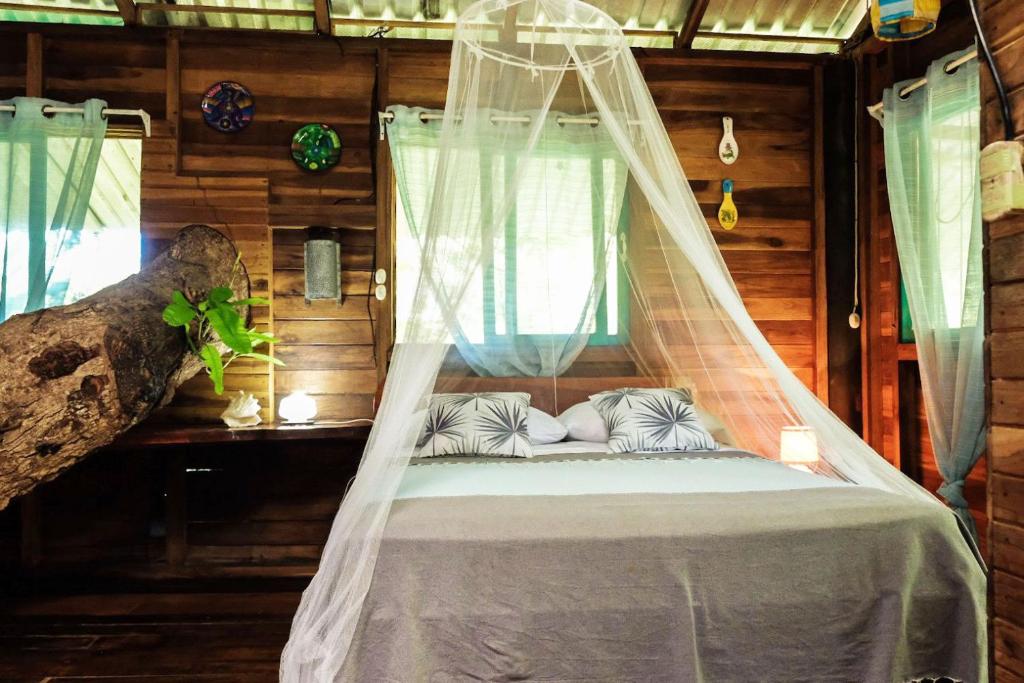 a bed in a room with a mosquito net at Playa Grande Lodge & Tree House in Cahuita