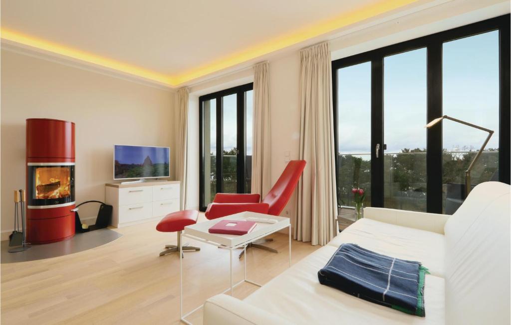 a white bedroom with a fireplace and red chairs at Penthouse Eden in Binz