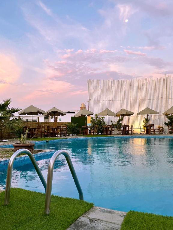 a large swimming pool with tables and umbrellas at Delfines de Chicama Hotel in Puerto Chicama