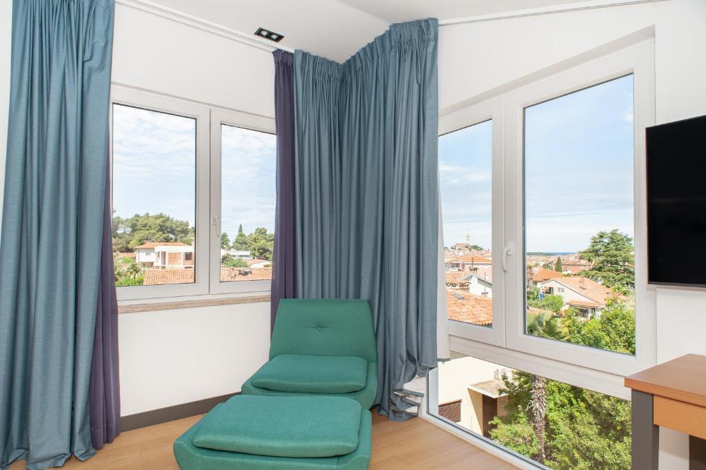 a room with a green chair and windows at Boutique hotel Lili in Rovinj