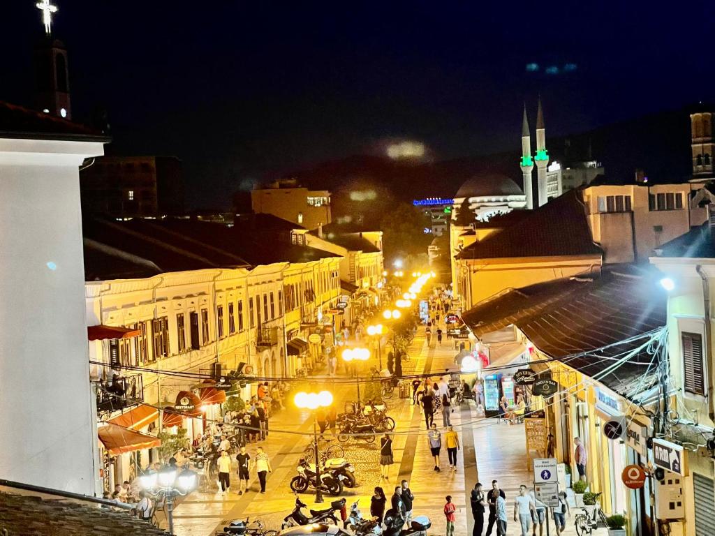 Una ciudad de noche con gente caminando por la calle en My Hostel en Shkodër